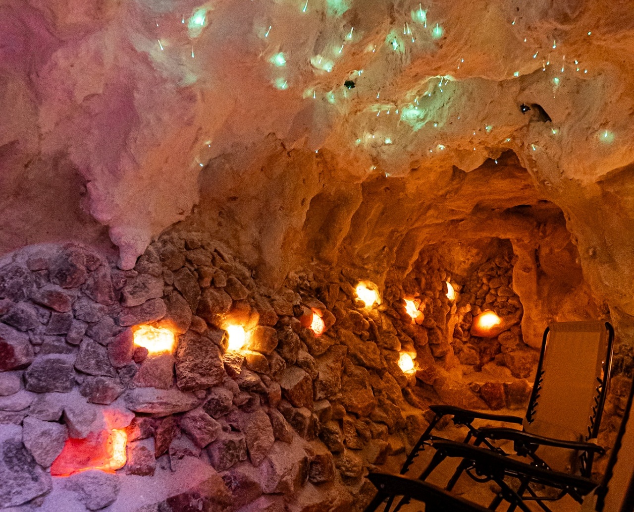 Relaksujące wnętrze groty solnej z podświetlanymi solnymi skałami i wygodnymi leżakami do odpoczynku