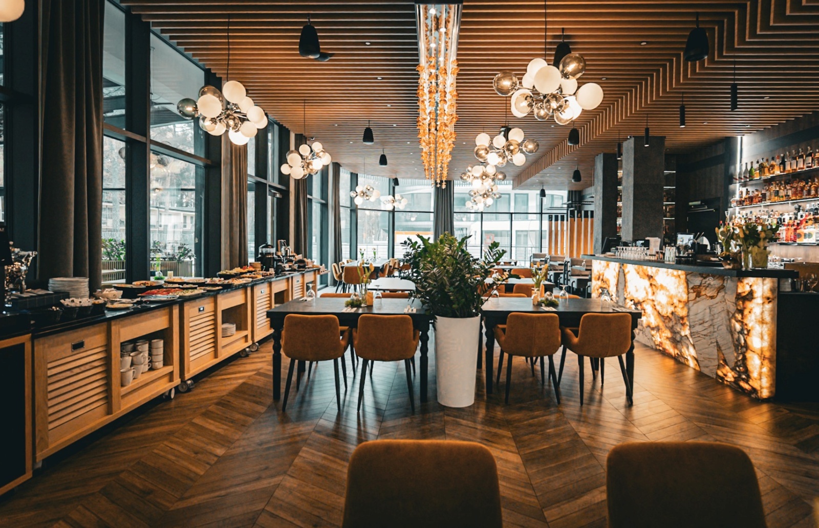 Nowoczesna hotelowa restauracja z bufetem, eleganckim oświetleniem, wygodnymi brązowymi krzesłami i marmurowym barem