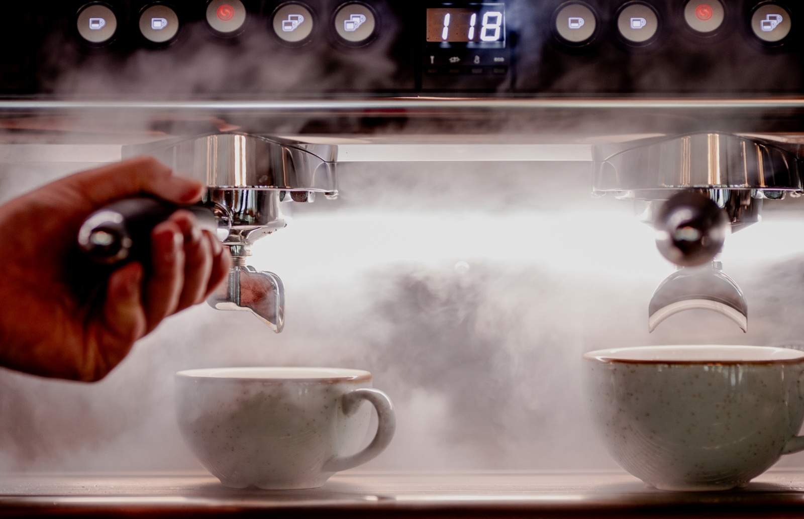 Ekspres do kawy przygotowujący parę dla świeżo zaparzonej kawy w ceramicznych filiżankach w hotelowej kawiarni