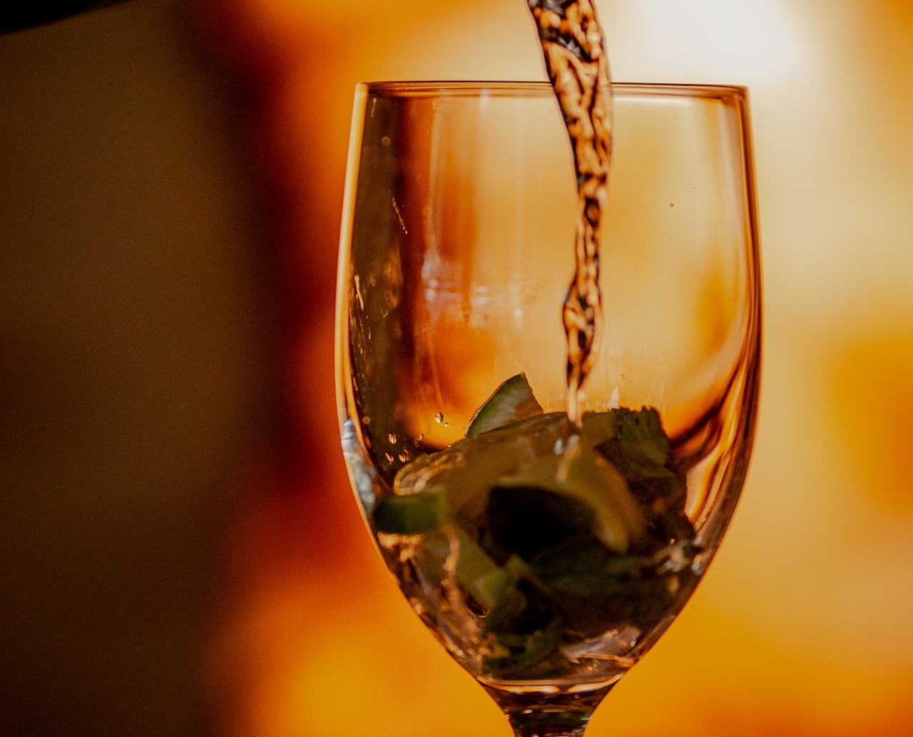 Napój nalewany do kieliszka z plasterkami cytryny i lodem w ciepłej, przytulnej atmosferze restauracji