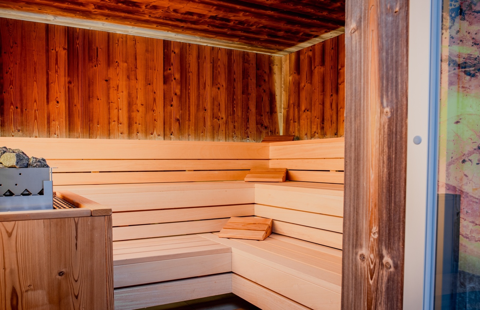 Przytulna sauna z jasnym drewnem, kamieniami do podgrzewania i ergonomicznymi oparciami dla relaksu gości