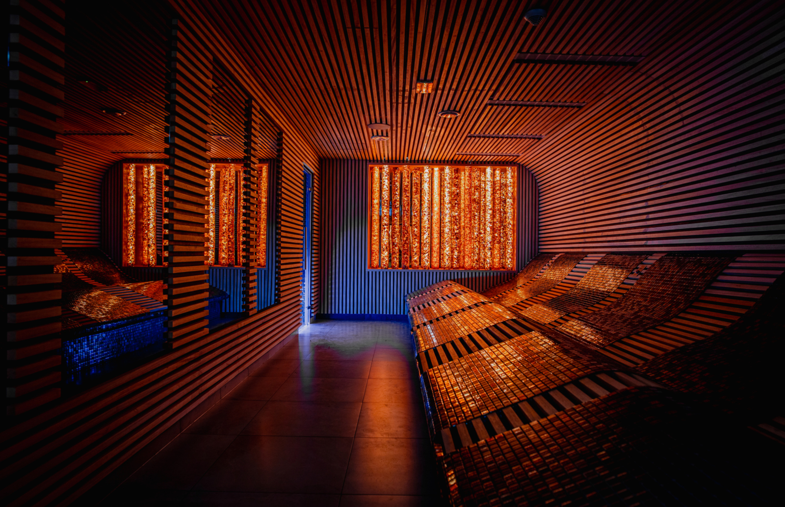 Przytulne pomieszczenie spa z podświetlanymi leżankami i nowoczesnym drewnianym wystrojem, idealne do relaksu