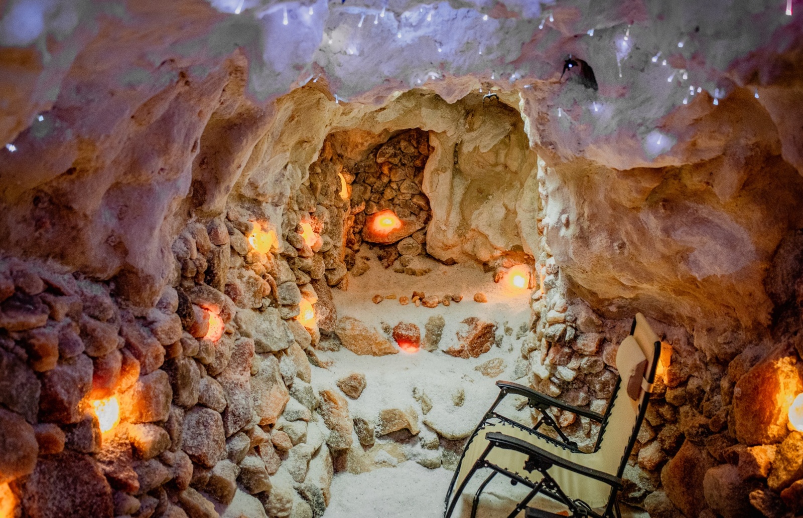 Kamienna grota solna z podświetlanymi kryształami soli, relaksujące miejsce z leżakiem do terapii solnej