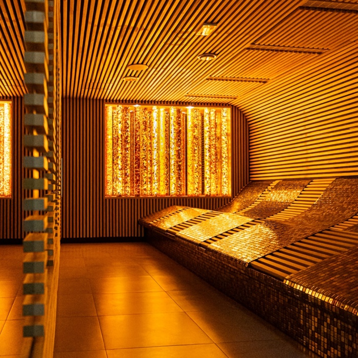 Przytulne miejsce relaksu w spa z podświetlanymi, wyprofilowanymi leżankami i nowoczesnym drewnianym wykończeniem ścian i sufitu