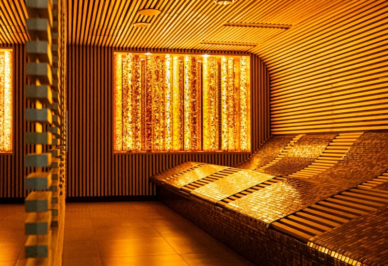 Przytulne miejsce relaksu w spa z podświetlanymi, wyprofilowanymi leżankami i nowoczesnym drewnianym wykończeniem ścian i sufitu