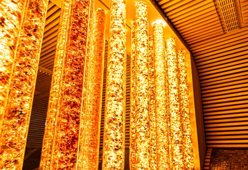 Relaksująca strefa spa z mozaikowymi siedziskami i ciepłym, nastrojowym oświetleniem w formie podświetlanych pionowych słupów.