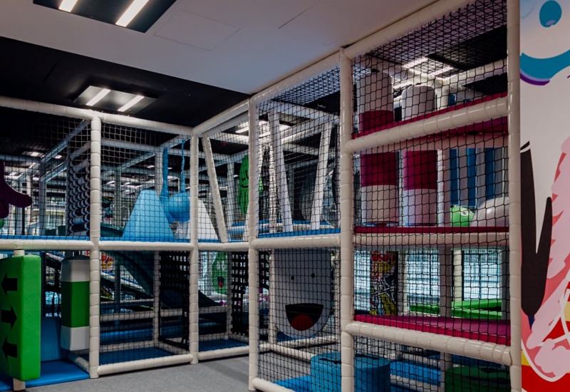 Kolorowy kryty plac zabaw dla dzieci z bezpiecznymi przeszkodami, zjeżdżalniami i miękkimi elementami do zabawy