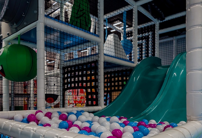 Kolorowy plac zabaw dla dzieci z podwójną zjeżdżalnią i basenem z kulkami w hotelowym centrum rozrywki dziecięcej