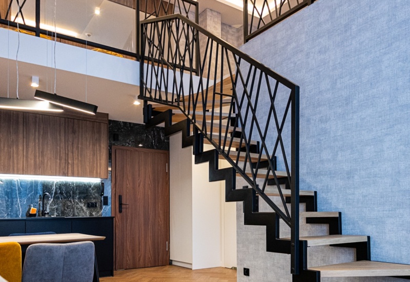 Nowoczesny apartament z otwartą kuchnią, drewnianą klatką schodową i designerskimi lampami sufitowymi