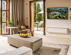 Bright suite with open doors to a private pool and garden terrace, featuring modern furnishings and outdoor seating area