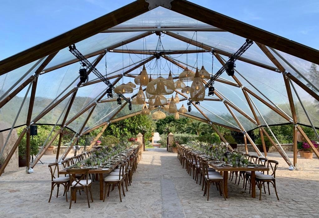 Große, mit vielen Blumen geschmückte Hochzeitstische mit einem transparenten Dach darüber