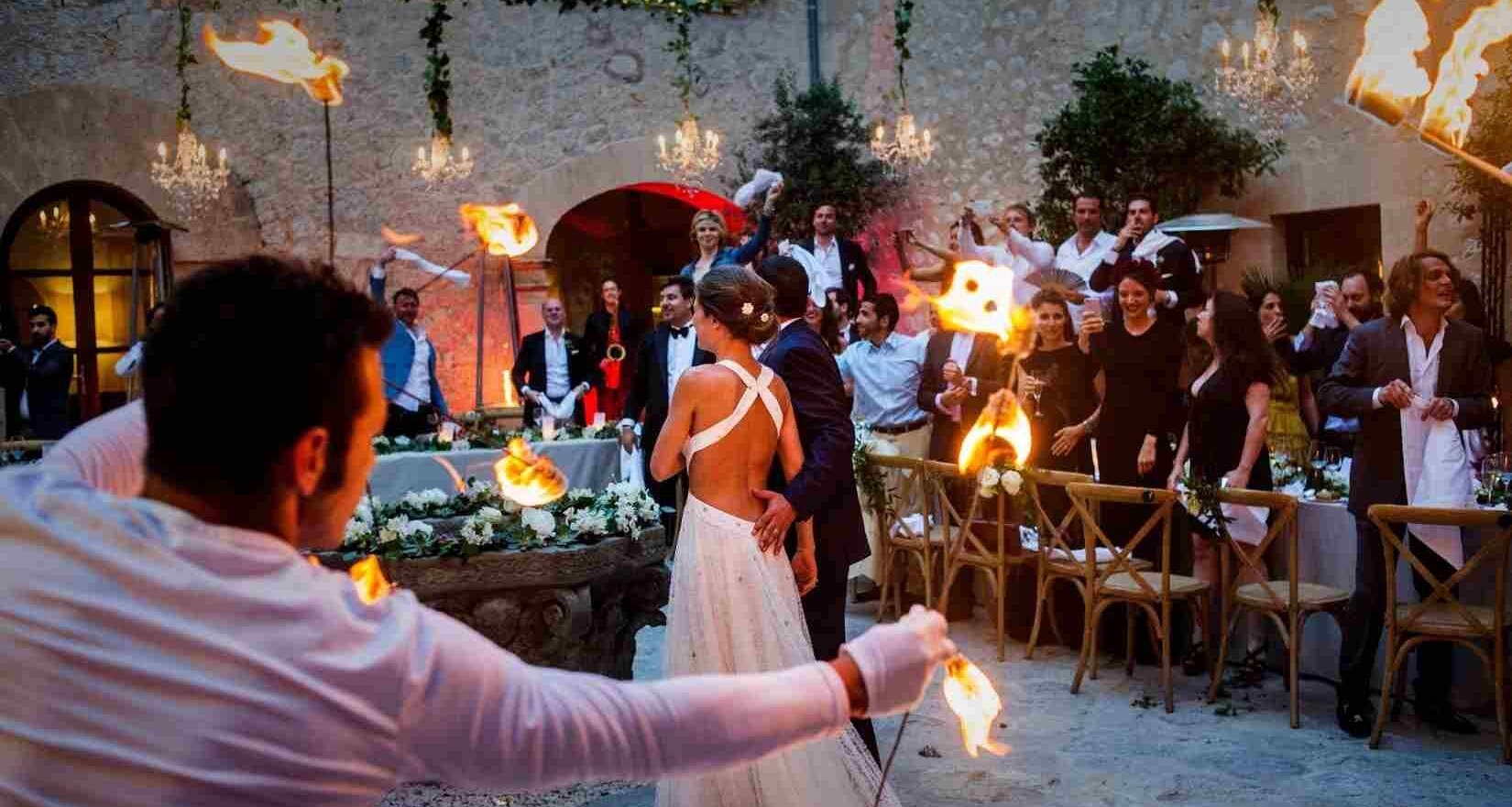 Ein Brautpaar steht inmitten einer Feier mit Hochzeitsgästen und einer Feuershow