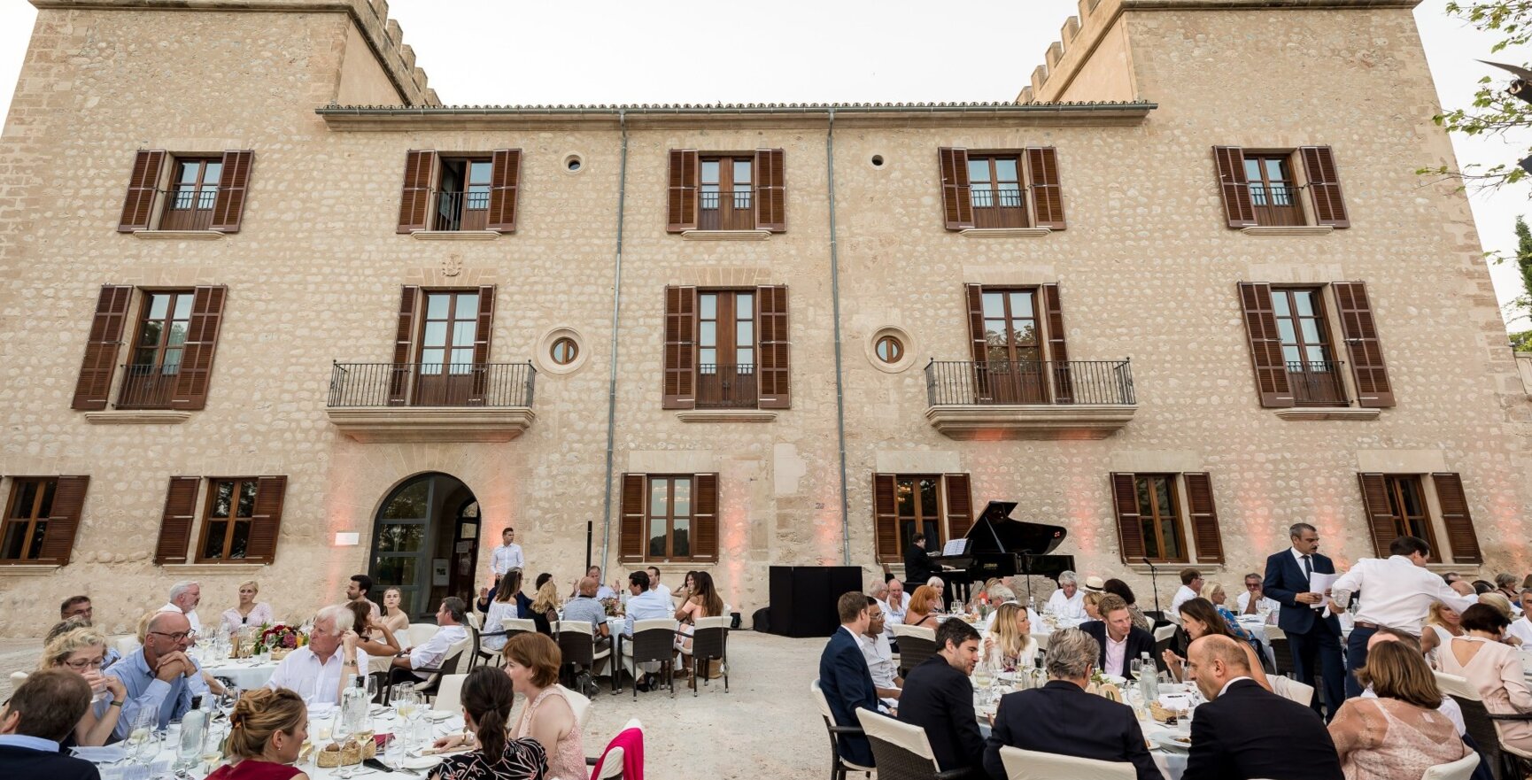 Hochzeitsgäste sitzen an runden Tischen vor einem mallorquinischen Hochzeitshotel