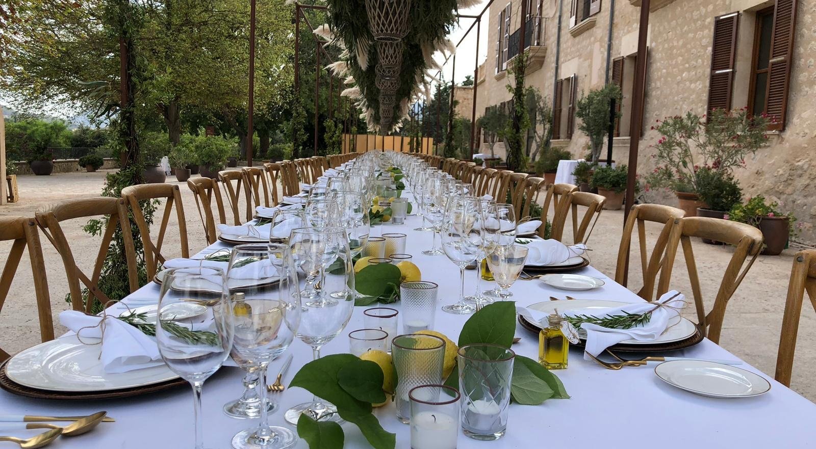 Mesa romántica en una boda en Mallorca con copas de vino, limones y hojas verdes