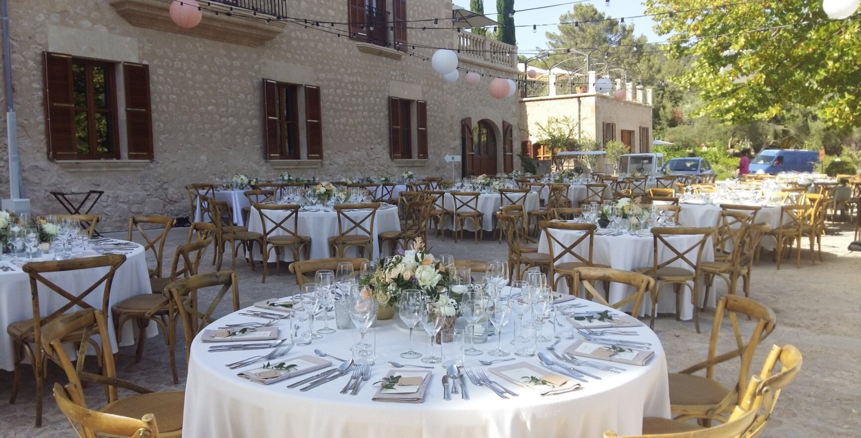 Mesas redondas con sillas de madera y decoración floral en una boda en Mallorca