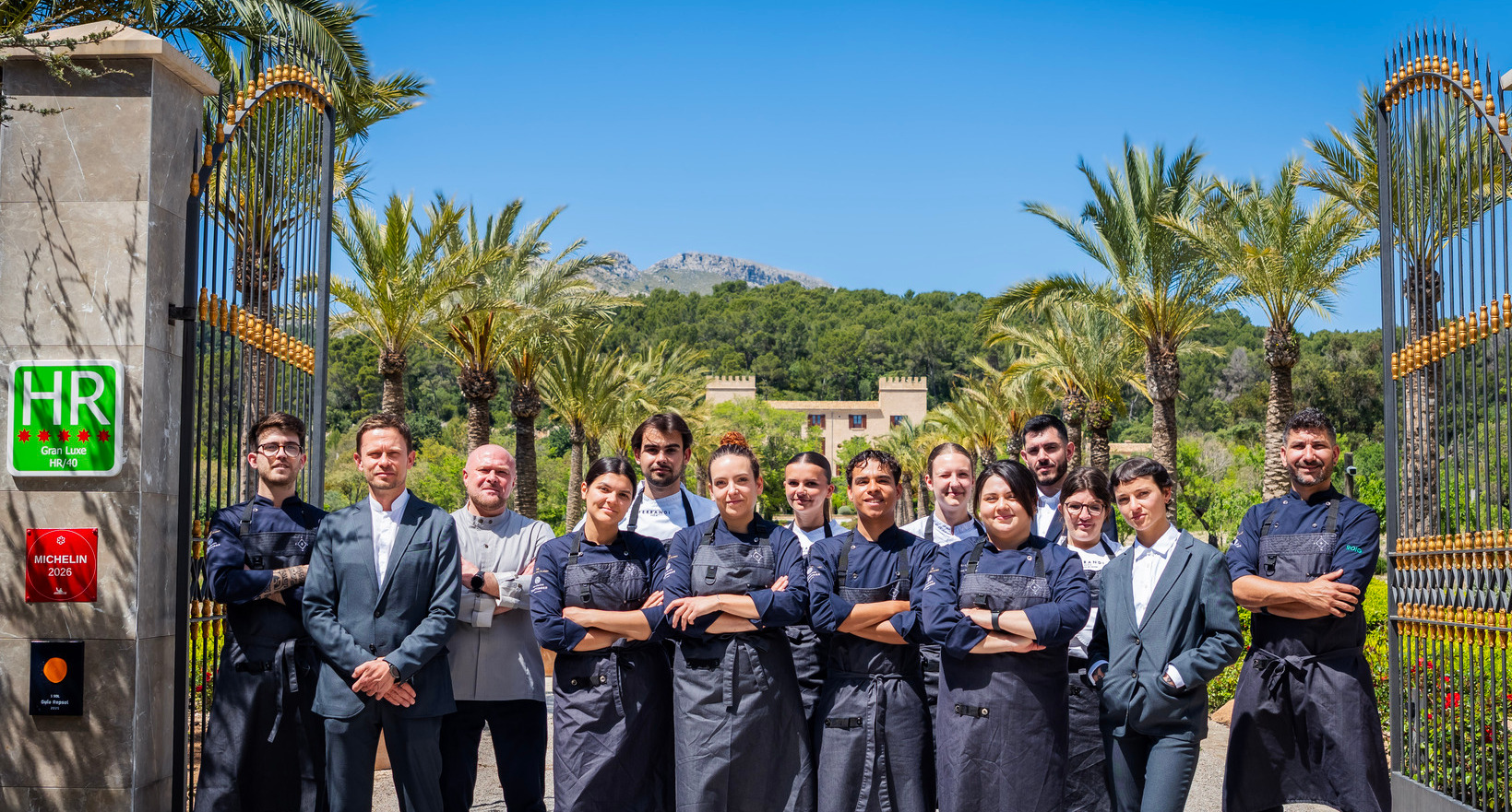 Equipo de cocina y recepción junto a elegante puerta de entrada, entrada flanqueada por palmeras y finca de lujo.