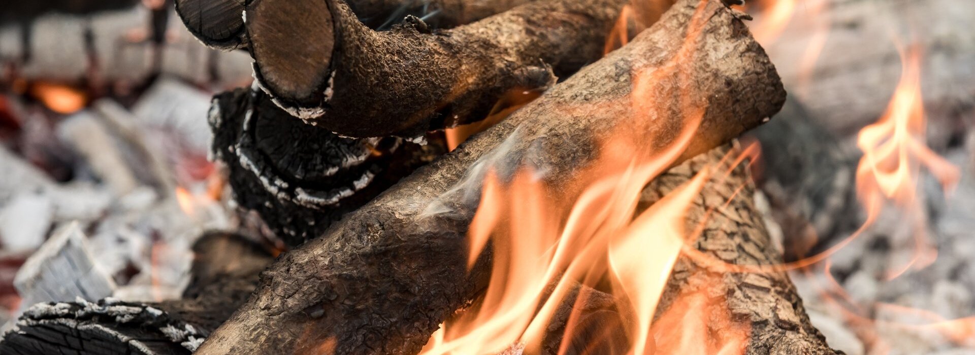 Warmes knisterndes Feuer mit brennenden Holzscheiten für eine gemütliche Lagerfeuer-Atmosphäre im Freien
