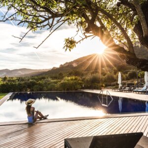 Sunny pool terrace at the luxury hotel in Mallorca with a woman sitting at the edge