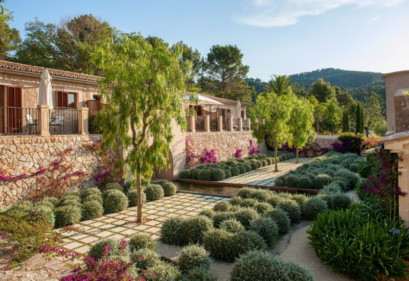 Ein sonniges Hotelgrundstück mit Steinmauern und Höfen mit Palmen im Vordergrund