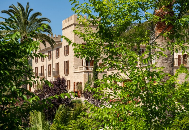 Grüne Bäume vor einem Schlosshotel auf Mallorca mit hellen Steinmauern