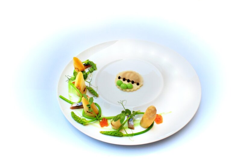 Weißer Teller mit einem Gourmet-Gericht, serviert mit Blumen in einer Hochzeitslocation auf Mallorca