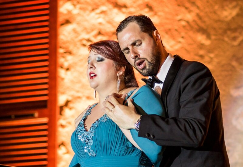 Zwei Opernsängerinnen stehen zusammen auf der Bühne und führen dramatisch ein Lied auf