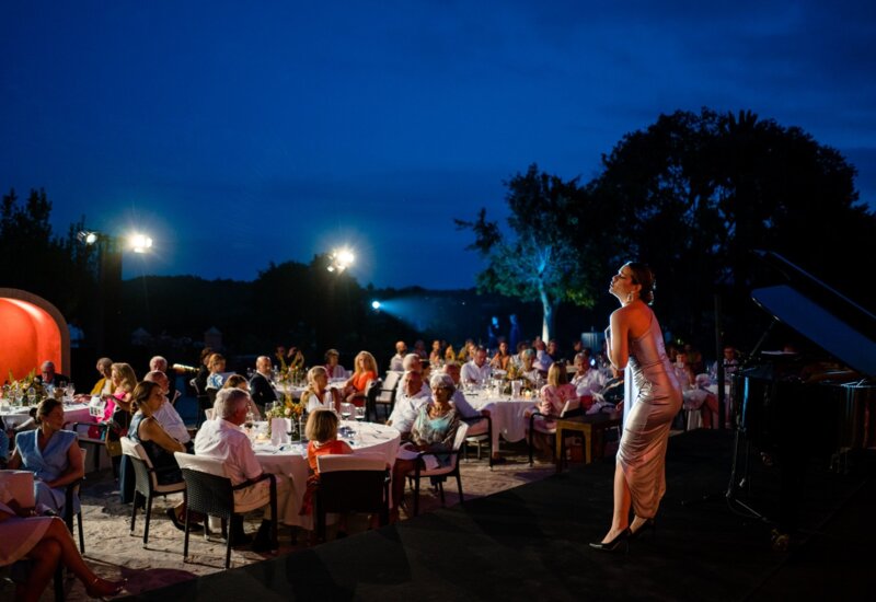 Eine Sängerin steht auf der Bühne und tritt auf, während die Hotelgäste zu Abend essen
