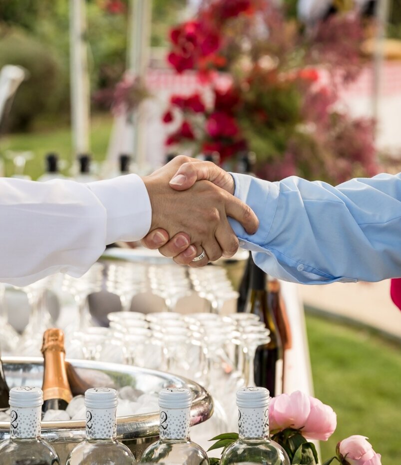 Zwei Männer schütteln sich die Hände über einem Tisch mit Champagnerflaschen im Luxushotel Mallorca