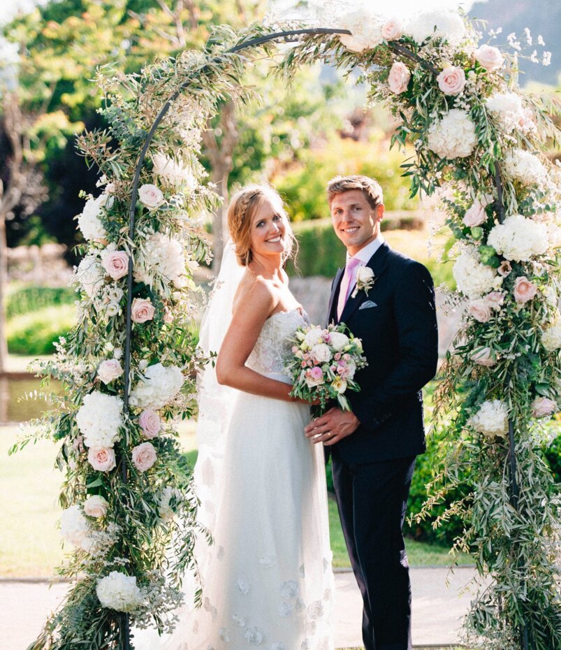 Una feliz pareja de novios frente al altar de flores de una boda en Mallorca