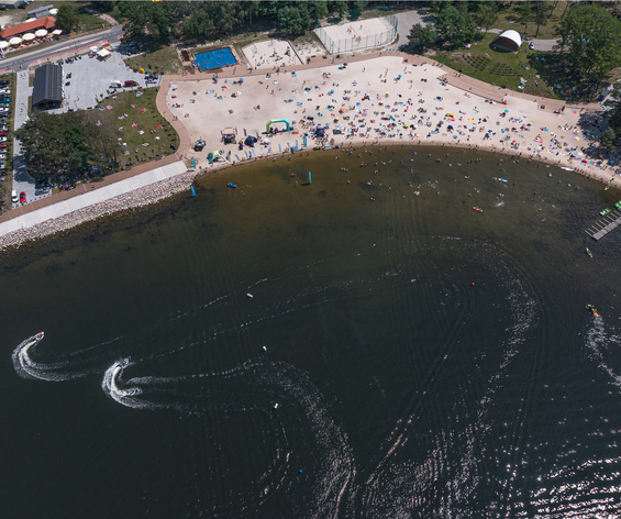 Piaszczysta plaża przy ośrodku z leżakami i parasolami, kąpieliskiem, pomostem, wypożyczalnią sprzętu i skuterami wodnymi.