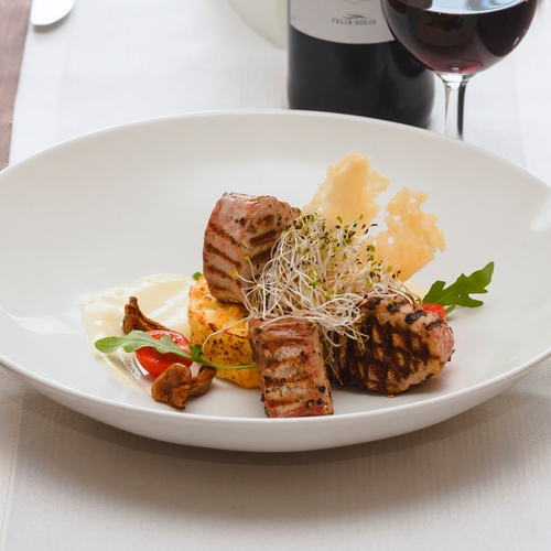 Grillowane medaliony mięsa na kremowym purée z pomidorkiem, kiełkami i chrupiącymi płatkami parmezanu, podane z kieliszkiem czerwonego wina
