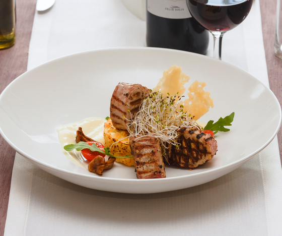 Grillowane medaliony mięsa na kremowym purée z pomidorkiem, kiełkami i chrupiącymi płatkami parmezanu, podane z kieliszkiem czerwonego wina