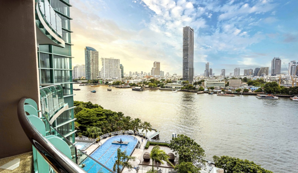 A scenic balcony view featuring a river and a vibrant city skyline in the background.
