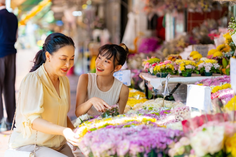 Two women shopping at the flower market in Bangkok, one of the best things to do near the Chao Phraya river 