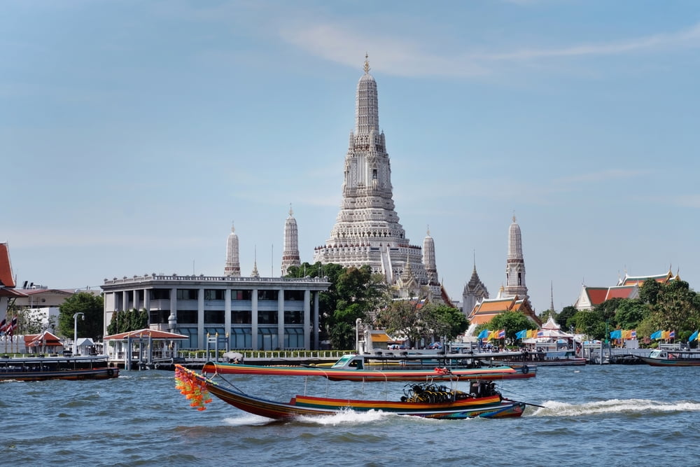 A view of the Chao Phraya river during day time with a boat zooming by