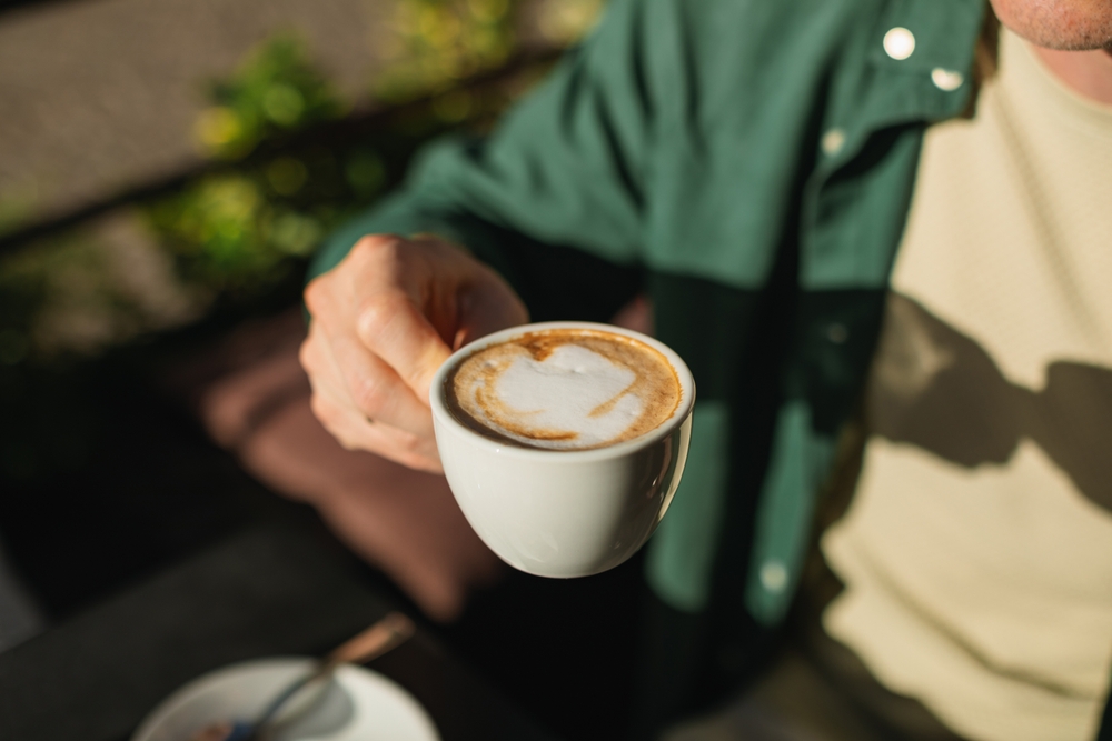 A man holding a cup of coffee at an outdoor cafe