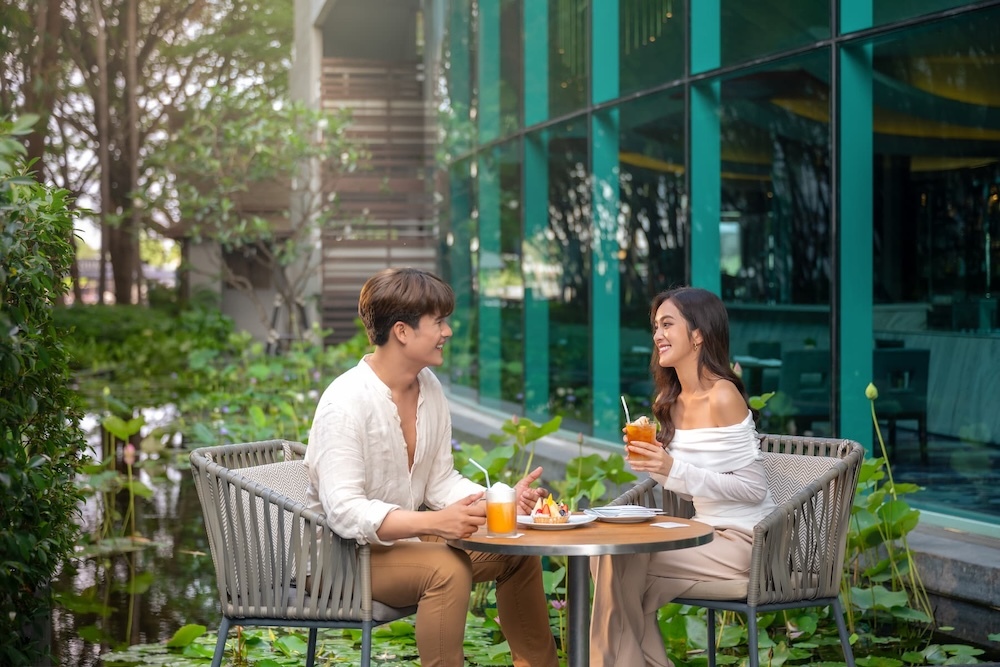 A couple enjoying drinks and light snacks in the outdoor seating area of Chatrium Hotel Riverside Bangkok
