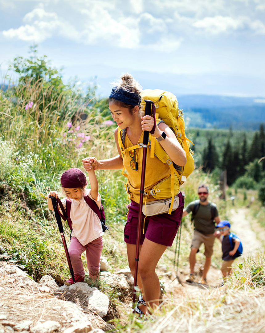女性と子供が木々と自然に囲まれた景色の良いトレイルを一緒にハイキングしています