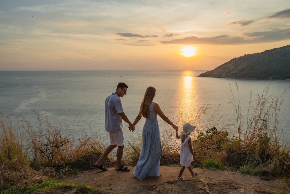 Parents and child watching the sunset at a scenic Phuket viewpoint