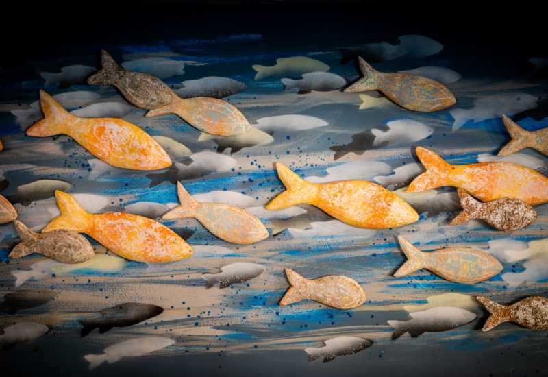 Textured orange and gray fish wall art over blue painted waves, coastal mural evoking a relaxed seaside ambiance