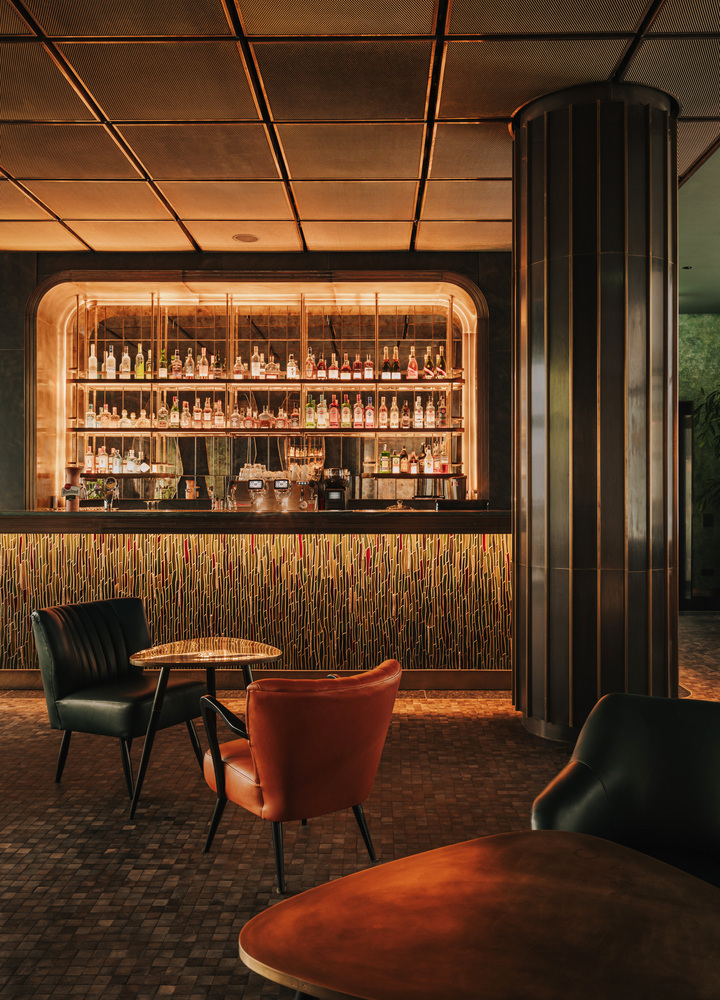 Bar w hotelu the Cyrus z mosiężnymi stolikami i obitymi skórą fotelami w klimatycznym oświetleniu