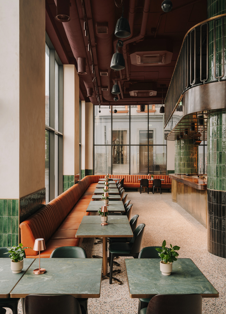 Bar w hotelu the Cyrus z mosiężnymi stolikami i obitymi skórą fotelami w klimatycznym oświetleniu