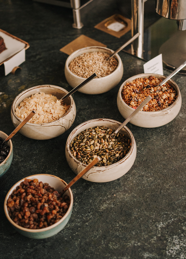Selection of breakfast cereals and toppings served in the elegant restaurant at the best hotel in Wrocław, presented in ceramic bowls on a stone breakfast buffet counter