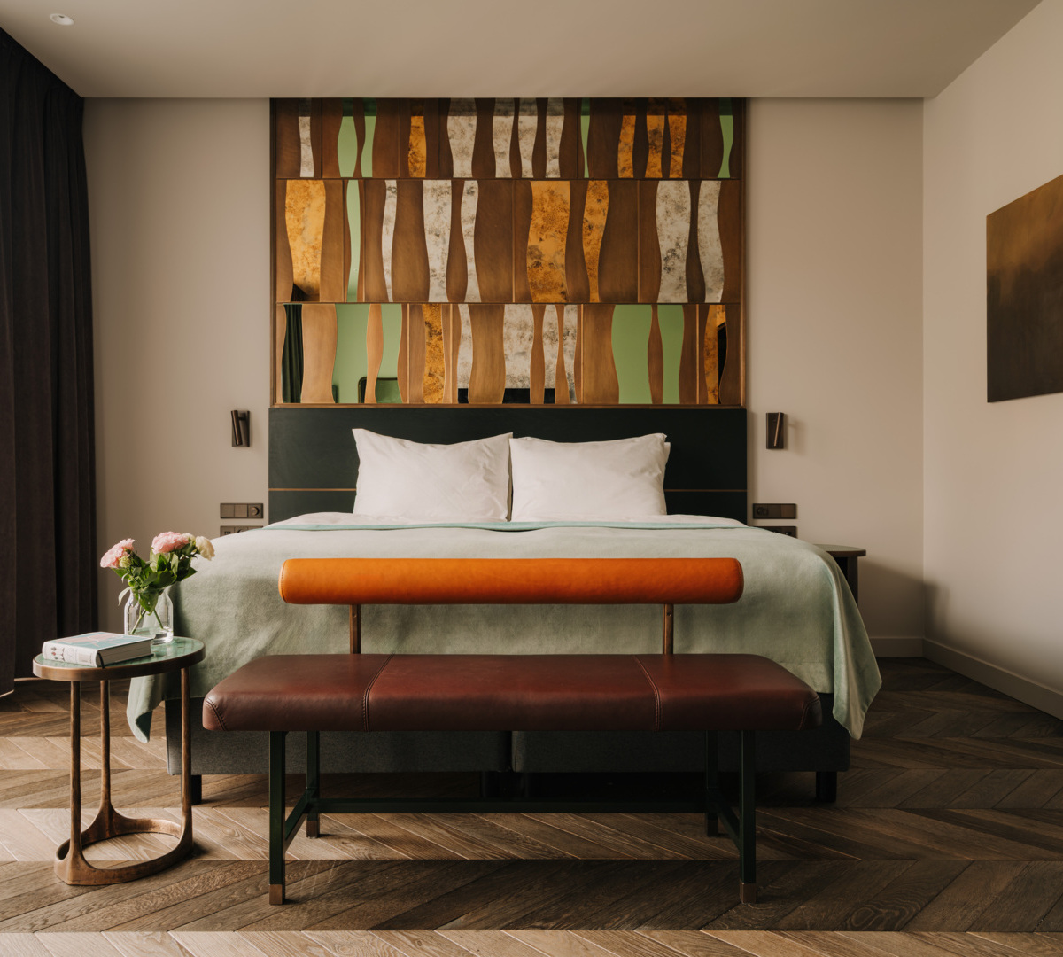 Nowoczesny pokój hotelowy z dużym łóżkiem, oryginalnym drewnianym zagłówkiem i elegancką ławką na drewnianej podłodze