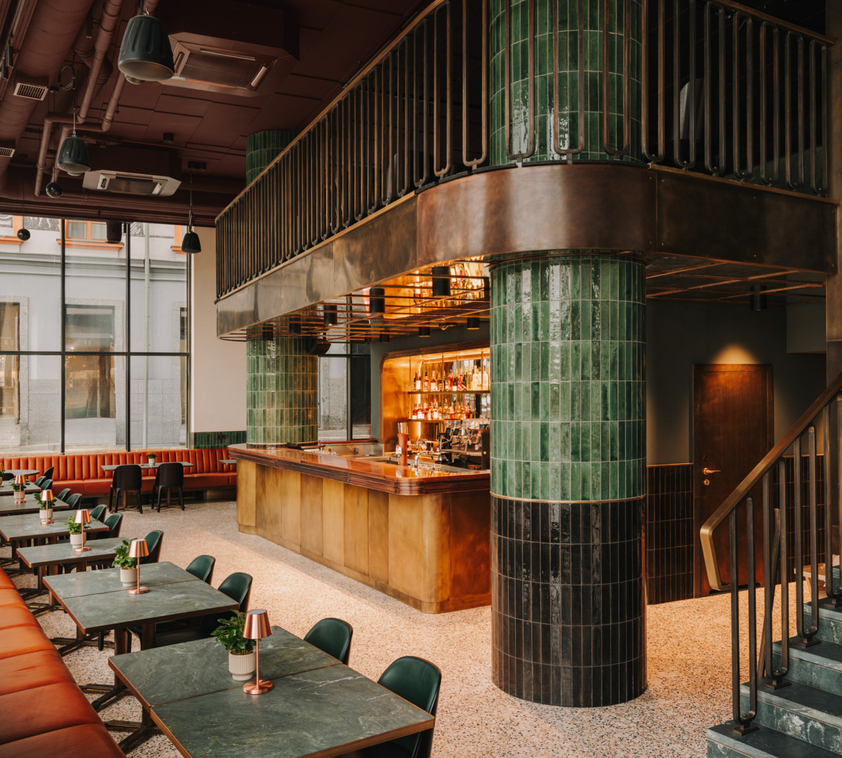 Nowoczesny hotelowy bar z zielonymi kafelkami, marmurowymi stolikami, skórzaną ławką i efektownym oświetleniem