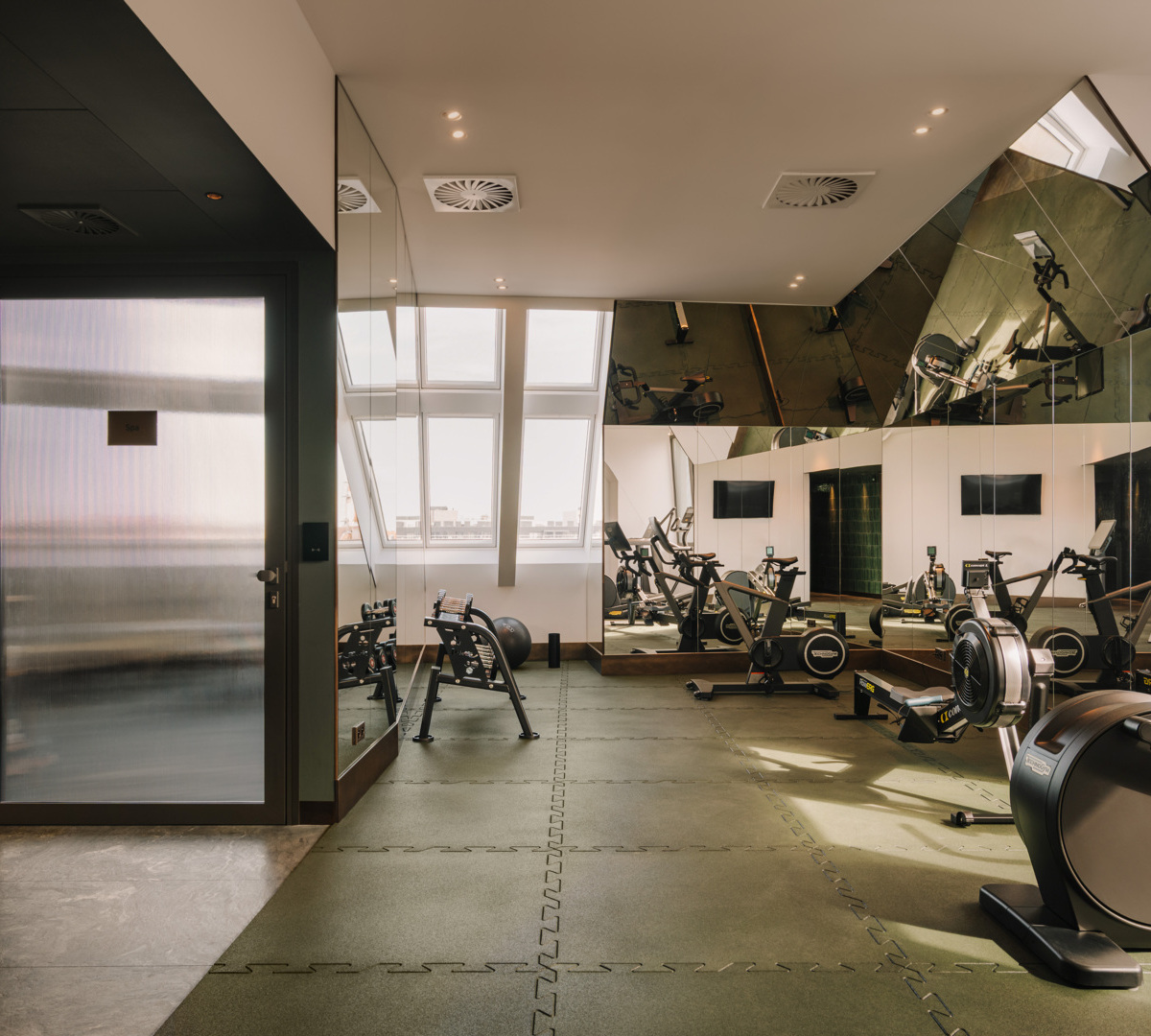Elegancka siłownia hotelowa z nowoczesnym sprzętem do ćwiczeń i dużymi lustrami odbijającymi światło dzienne