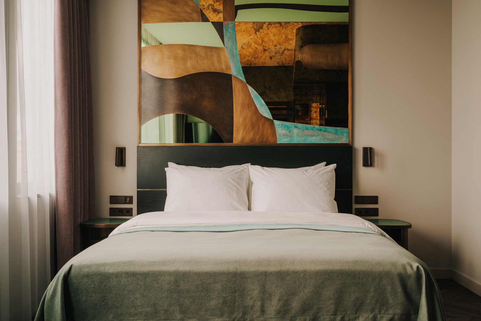 Elegantes Hotelzimmer im The Cyrus mit Doppelbett, weisser Bettwaesche, Samtdecke und kuenstlerischem Kopfteil in warmen Naturtoenen, sanftes Licht und ruhige Atmosphaere