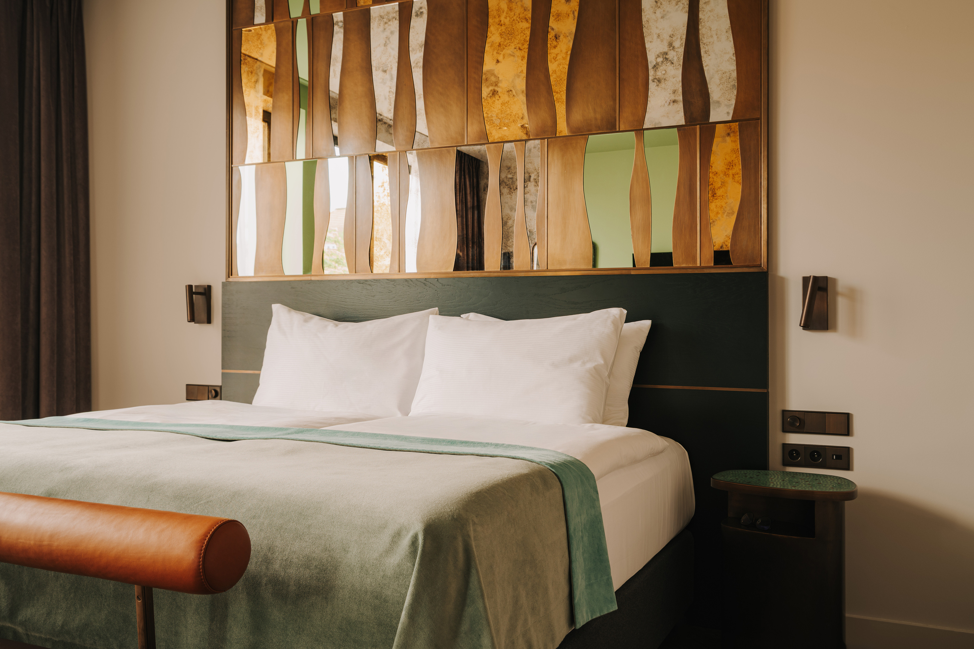wygodne podwójne, zaścielona łóżko z seledynową narzutą w pokoju hotelowym The Cyrus we Wrocławiu