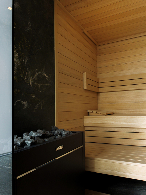 Nowoczesna sauna w hotelu The Cyrus we Wrocławiu z drewnianymi ławkami, naturalnym wykończeniem z jasnego drewna oraz designerskim piecem z kamieniami w strefie wellness i spa.