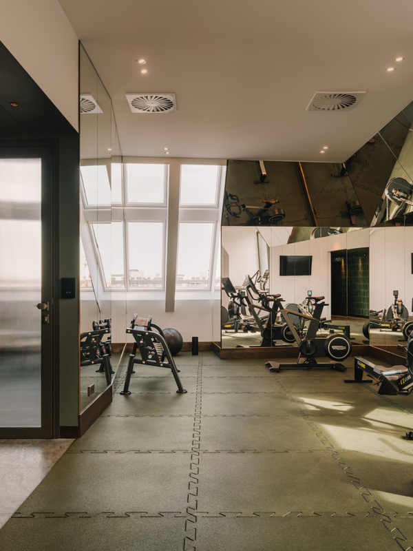 Nowoczesna siłownia hotelowa z nowoczesnym sprzętem do ćwiczeń i dużymi lustrami odbijającymi światło dzienne
